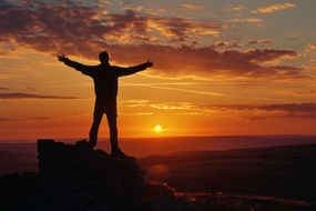 日暮黄昏站在高山之巅人物剪影图片